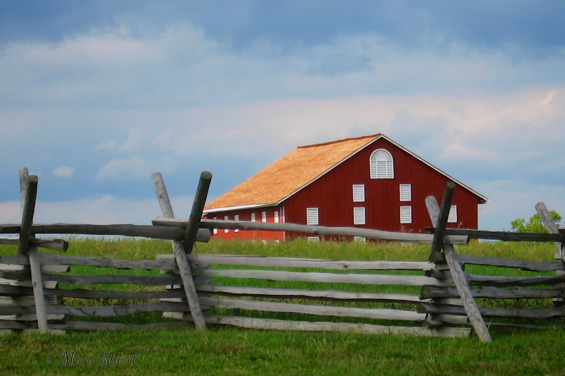 A red barn against a green hillside and blue sky in Gettysburg